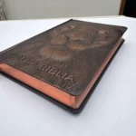 Biblia León de Judá en ángulo mostrando el relieve del león y el canto cobrizo – imagen 3