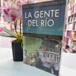 Libro La gente del río de pie junto a una orquídea en la librería – imagen 6